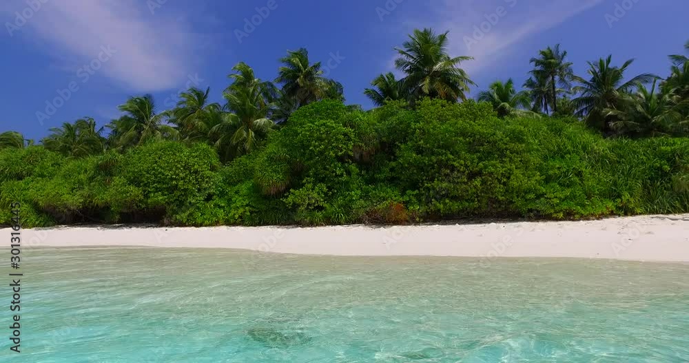 A Lush Green Island Beside the Shallow Ocean Under the Bright Blue Sky in Hawaii - Wide Shot A Lush Green Island Beside the Shallow Ocean Under the Bright Blue Sky in Hawaii - Wide Shot