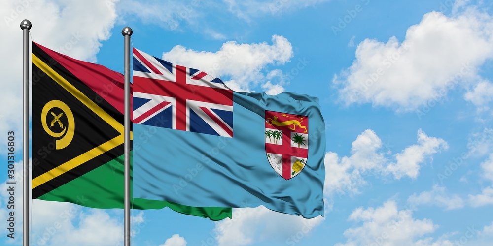 Vanuatu and Fiji flag waving in the wind against white cloudy blue sky together. Diplomacy concept, international relations.