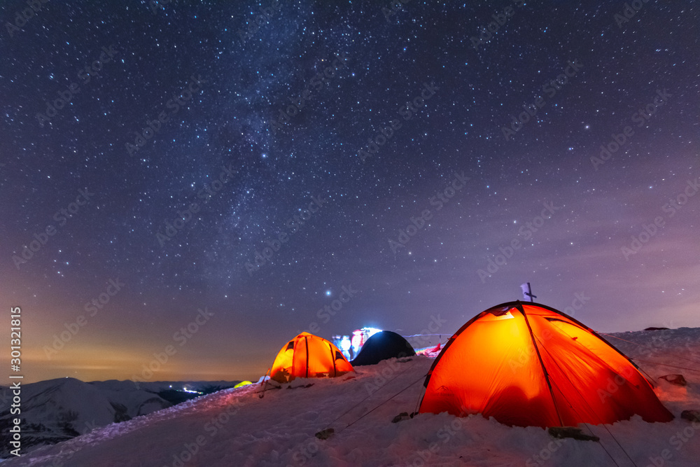 Great bright campsite with colorful tourist tents, on top in the Ukrainian Carpathian Mountains, at night with views of the stars and the Milky Way - obrazy, fototapety, plakaty 