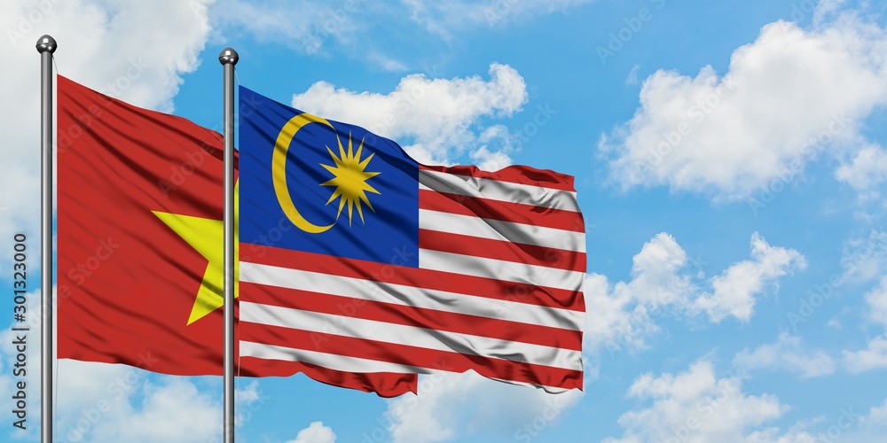 Vietnam and Malaysia flag waving in the wind against white cloudy blue sky together. Diplomacy concept, international relations.