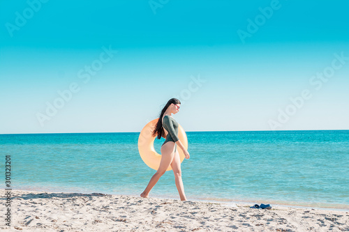 Portrait of a girl in pink glasses and with an orange rubber ring on the beach.