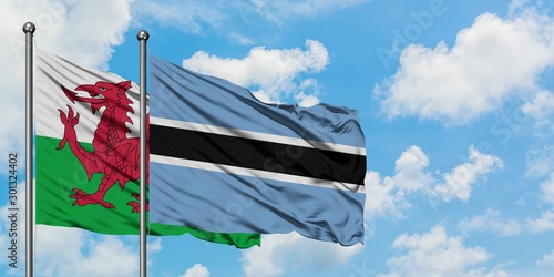 Wales and Botswana flag waving in the wind against white cloudy blue sky together. Diplomacy concept, international relations.