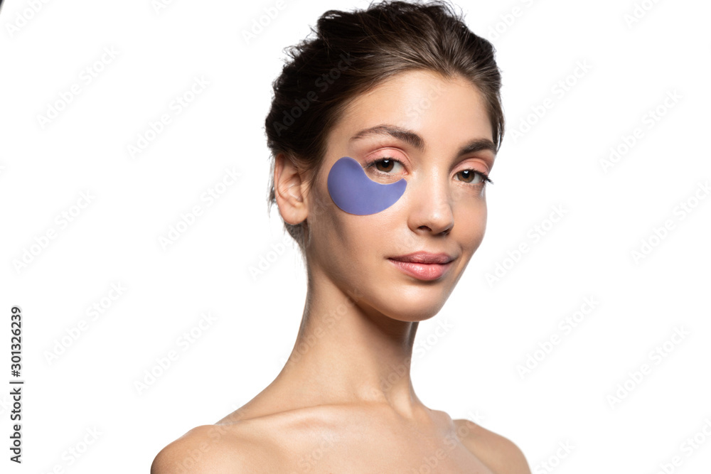 Studio portrait of smiling girl with beauty patch under eye looking at camera. Attractive naked young brunette woman caring for skin around eyes. Natural organic facial therapy. Fresh soft skin Studio portrait of smiling girl with beauty patch under eye looking at camera. Attractive naked young brunette woman caring for skin around eyes. Natural organic facial therapy. Fresh soft skin