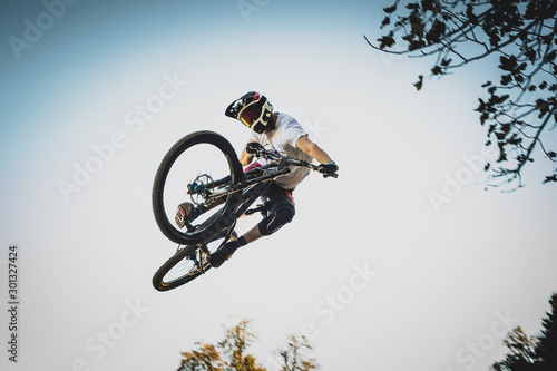 Fotografie Mountain biker jumping over a dirt jump.