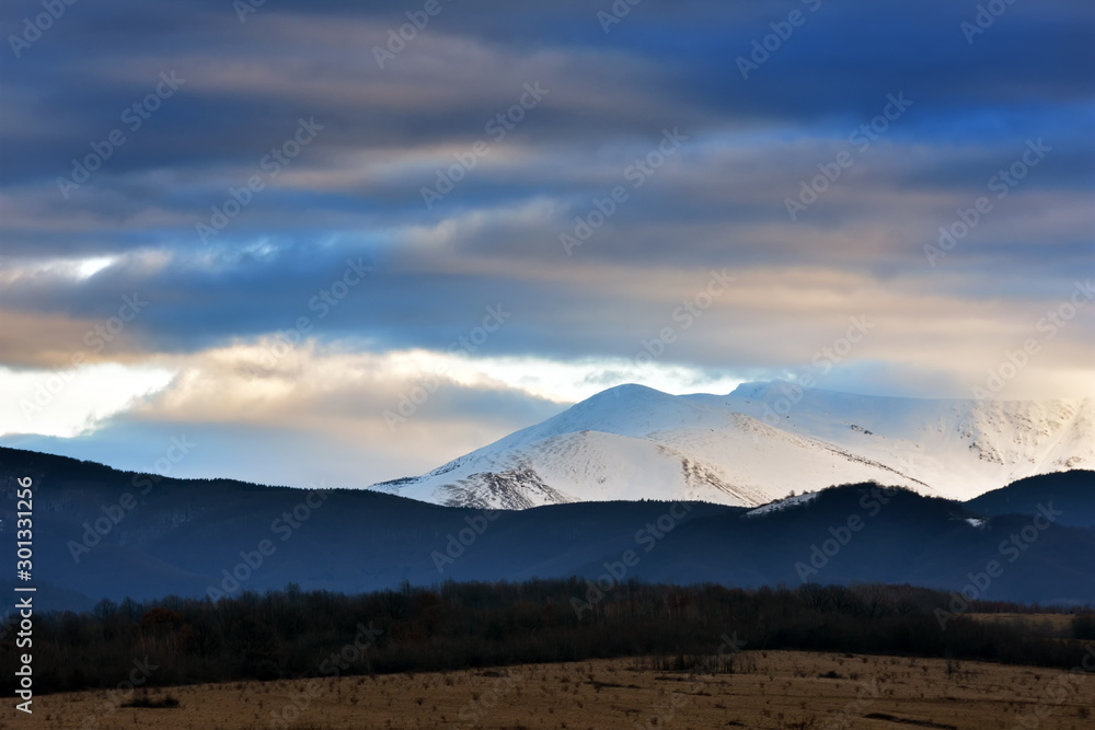Mountain covered in snow in late Autumn at sunset