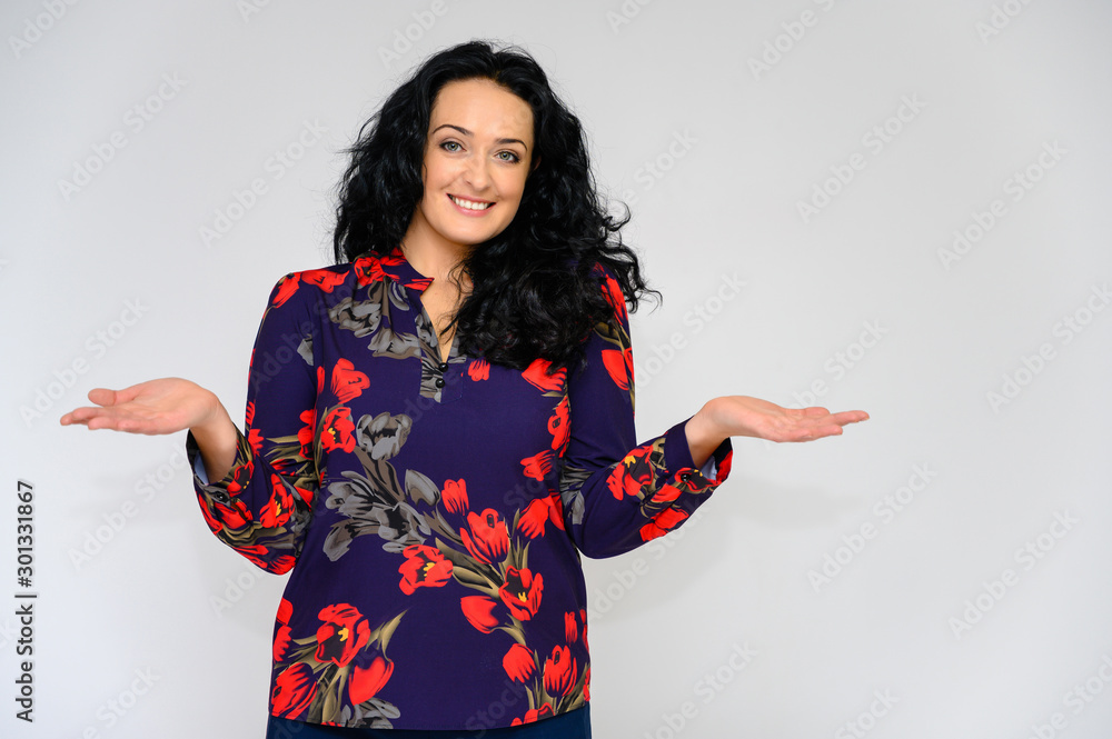 Portrait of a pretty brunette woman with long curly hair on a white background in a color blouse. He stands in front of the camera, smiles, talks in various poses with emotions. Portrait of a pretty brunette woman with long curly hair on a white background in a color blouse. He stands in front of the camera, smiles, talks in various poses with emotions.