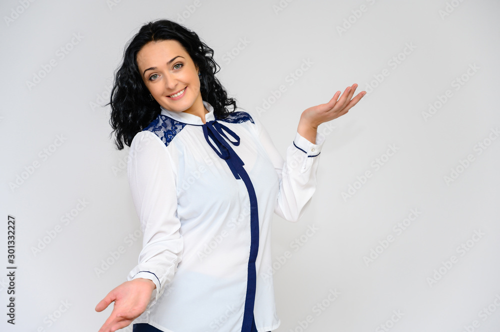 Portrait of a pretty brunette woman with long curly hair on a white background in a white blouse. He stands in front of the camera, smiles, talks in various poses. Portrait of a pretty brunette woman with long curly hair on a white background in a white blouse. He stands in front of the camera, smiles, talks in various poses.