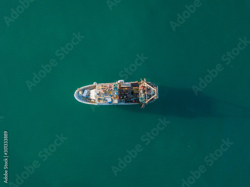 Aerial view of fishing boat anchored on ocean. Peaceful scene on water. Concept of traditional fishing in Europe.