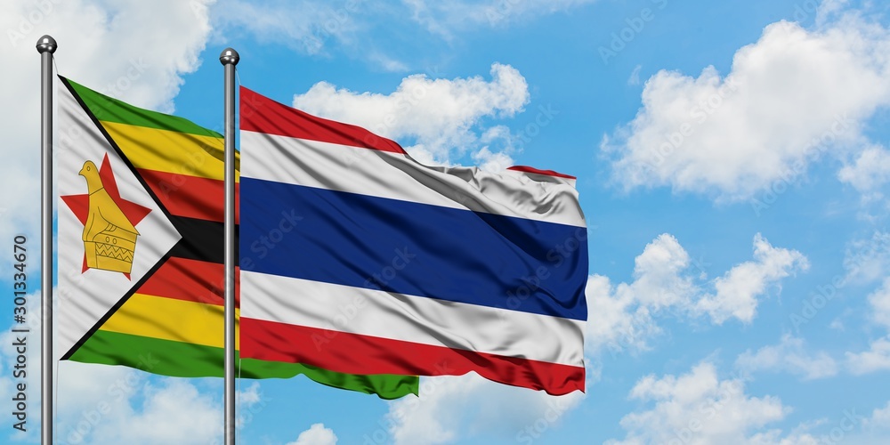 Zimbabwe and Thailand flag waving in the wind against white cloudy blue sky together. Diplomacy concept, international relations.