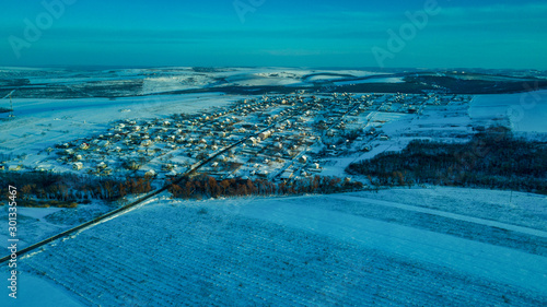aerial view village among the fields and forests in winter. winter landscape snow covered field and trees in countryside. © Igor Syrbu