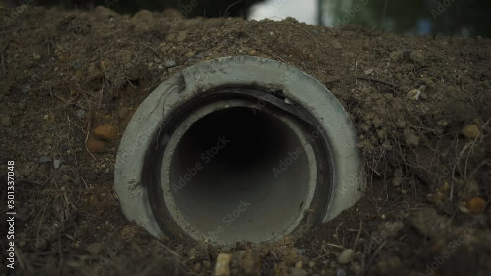 Sewer pipe hole in the street near road during sunny afternoon in France. Concrete tube. 4K UHD. Sewer pipe hole in the street near road during sunny afternoon in France. Concrete tube. 4K UHD.