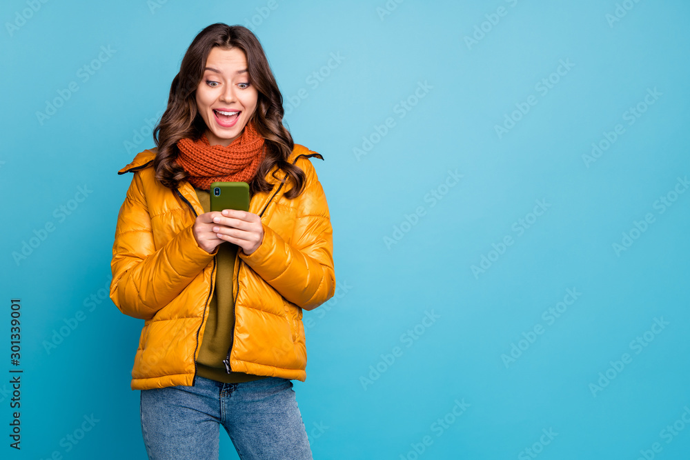 Photo of pretty millennial lady hold telephone read positive comments enjoy  followers wear stylish autumn windbreaker jeans scarf isolated blue color  background Stock Photo | Adobe Stock