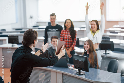 Hands up. Group of young people in casual clothes working in the modern office