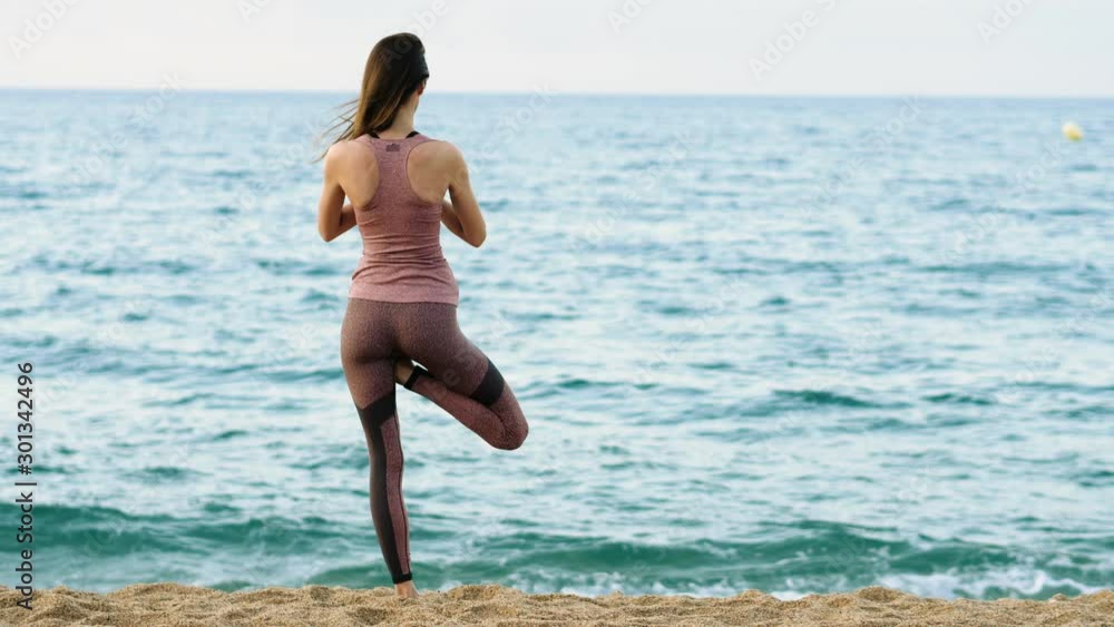 Young beautiful woman in sportswear practicing yoga and meditation at beach. Spain. 4K Young beautiful woman in sportswear practicing yoga and meditation at beach. Spain. 4K