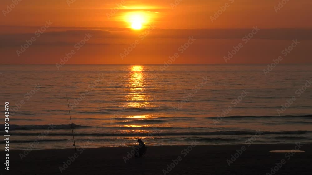 Old fisherman on beach at sunrise checking fishing rod Old fisherman on beach at sunrise checking fishing rod