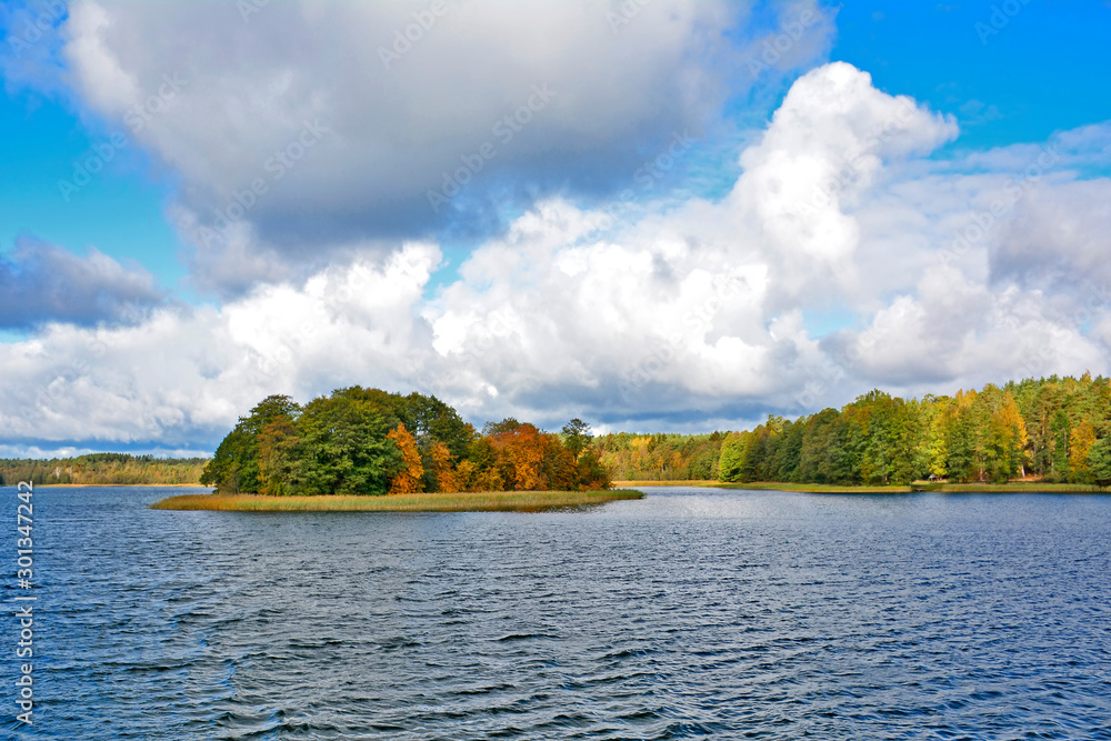 Autumn colors on the lake and blue sky with clouds