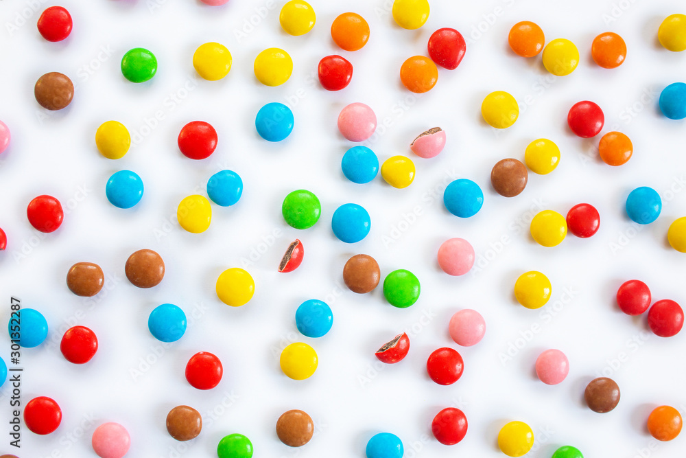 Scattered multi-colored small round candies. Chocolate dragees in multi-colored glaze on a white background