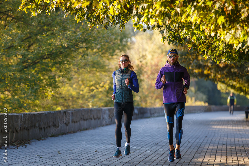 Obraz premium Young couple running in autumn park in the morning
