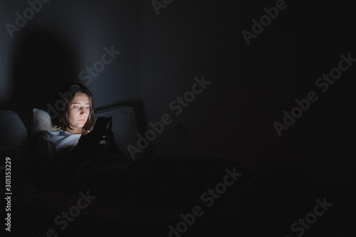 Φωτογραφία Woman in bed uses phone late at night