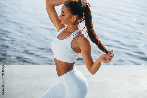 Posing for the camera. Young fitness woman with slim body type is outdoors