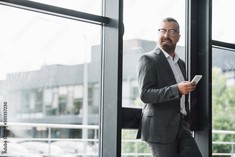 handsome businessman in formal wear and glasses holding smartphone handsome businessman in formal wear and glasses holding smartphone
