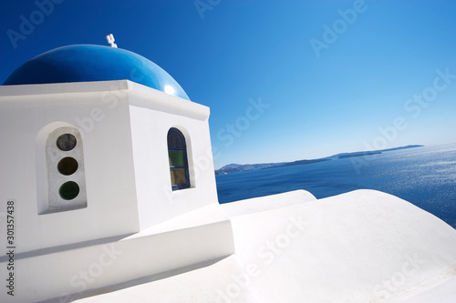Classic Greek island blue church dome standing over glittering Mediterranean sea in the Santorini caldera