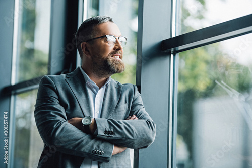 handsome businessman in formal wear and glasses looking away