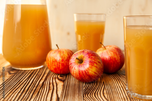 Ripe apples and freshly squeezed juice in glasses on a wooden table