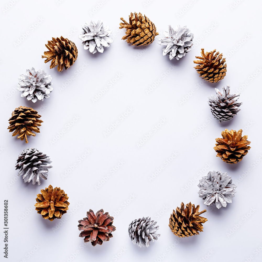 Painted pine cones frame on light grey background, Christmas golden and silver decorations flat lay, copy space, top view Painted pine cones frame on light grey background, Christmas golden and silver decorations flat lay, copy space, top view