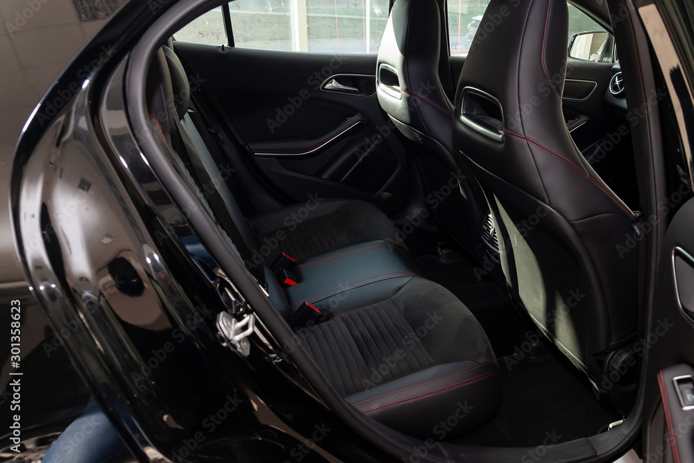 Clean after washing the rear passenger seats of matte black genuine leather inside the interior of an expensive suv, preparation before selling the car. Auto service industry. detailing cleaning.