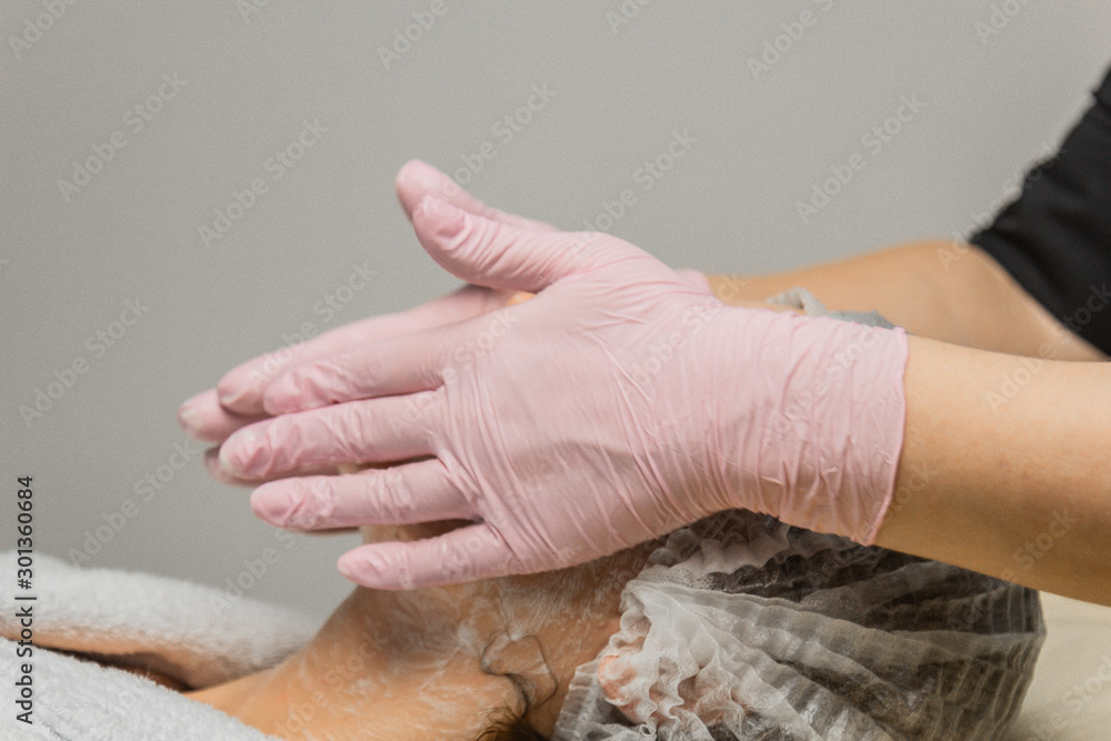 Fototapeta premium concept beautician. The hands of a cosmetologist put cream on the face of a woman. Beautician applies a cream to the face of the girl.