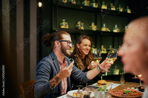 Group of best friends sitting in restaurant, having dinner, drinking wine and having fun.