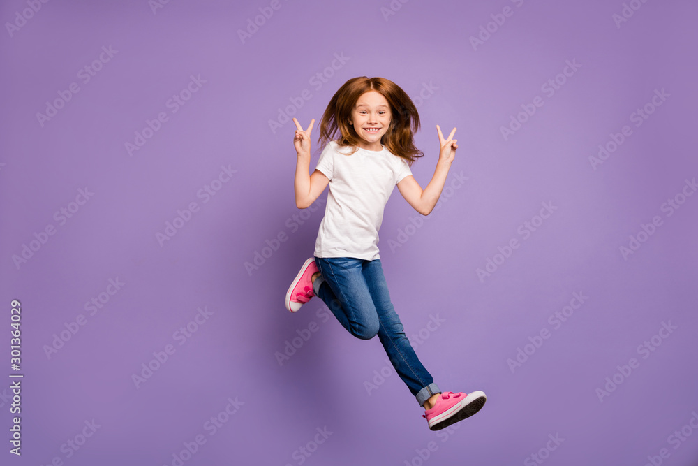 Full size profile photo of funky small foxy lady jumping high rejoicing walking street showing v-sign symbols wear casual white t-shirt jeans isolated purple background