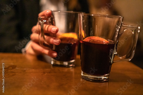 Beauty, elegant business woman with two glasses of mulled wine with orange and lemon inside the bar in basement. Wroclaw, Poland