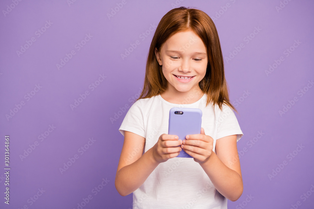 Photo of pretty little ginger lady holding telephone hands reading blog post interesting children useful information wear white t-shirt isolated purple background Photo of pretty little ginger lady holding telephone hands reading blog post interesting children useful information wear white t-shirt isolated purple background