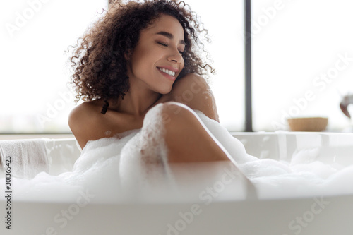 Charming Afro American woman relaxing in bathtub