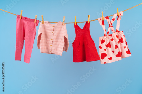 Baby girl clothes pinned on a clothesline against blue background