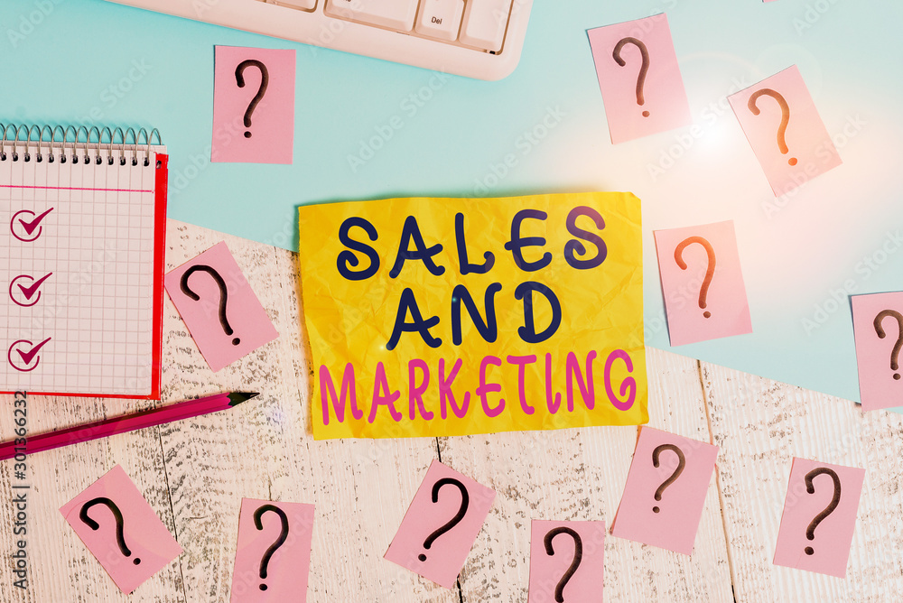 Writing note showing Sales And Marketing. Business concept for Promotion Selling Distribution of Goods or Services Writing tools and scribbled paper on top of the wooden table