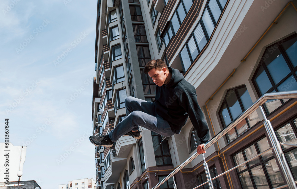 Young man doing parkour in the city at daytime. Conception of extreme sports