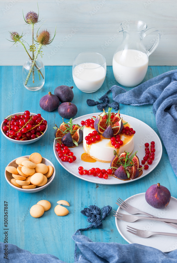 No bake cheesecake with salt caramel glaze embellished with fresh currant and figs with twigs of real rosemary herbs. Blue wooden table background. No bake cheesecake with salt caramel glaze embellished with fresh currant and figs with twigs of real rosemary herbs. Blue wooden table background.