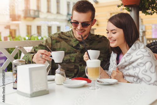 Couple in love sit in cafe outdoor, urban background.