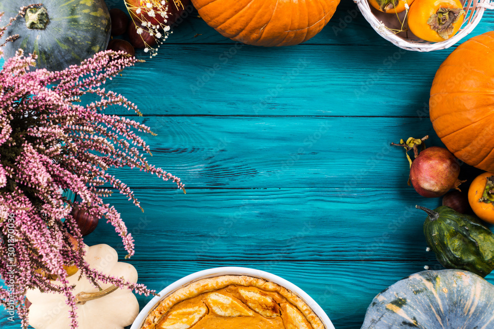 Autumn thanksgiving moody background with pumpkin pie, different pumpkins, fall fruit and flowers on green rustic wooden table. Flat lay - obrazy, fototapety, plakaty 