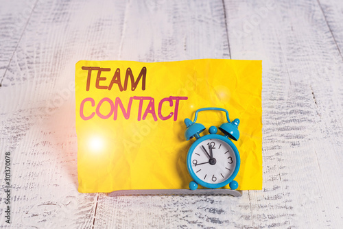 Word writing text Team Contact. Business photo showcasing The interaction of the individuals on a team or group Mini blue alarm clock stand tilted above buffer wire in front of notepaper photo