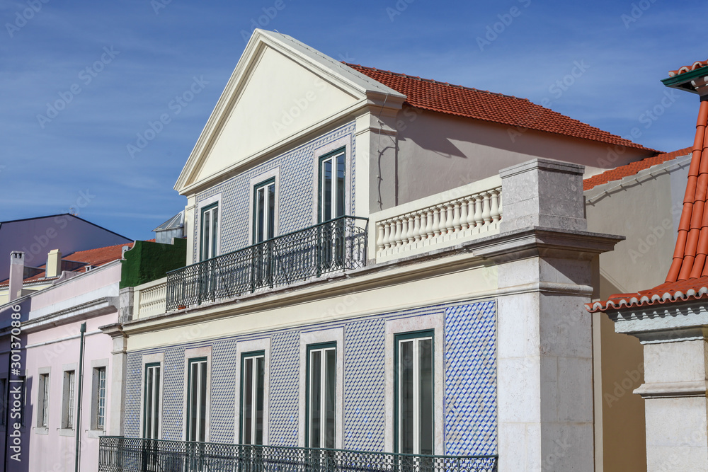 A beautiful architecture of the traditional tiled walled facade with large glass doors and windows and the iron balcony in the city of Lisbon in Portugal