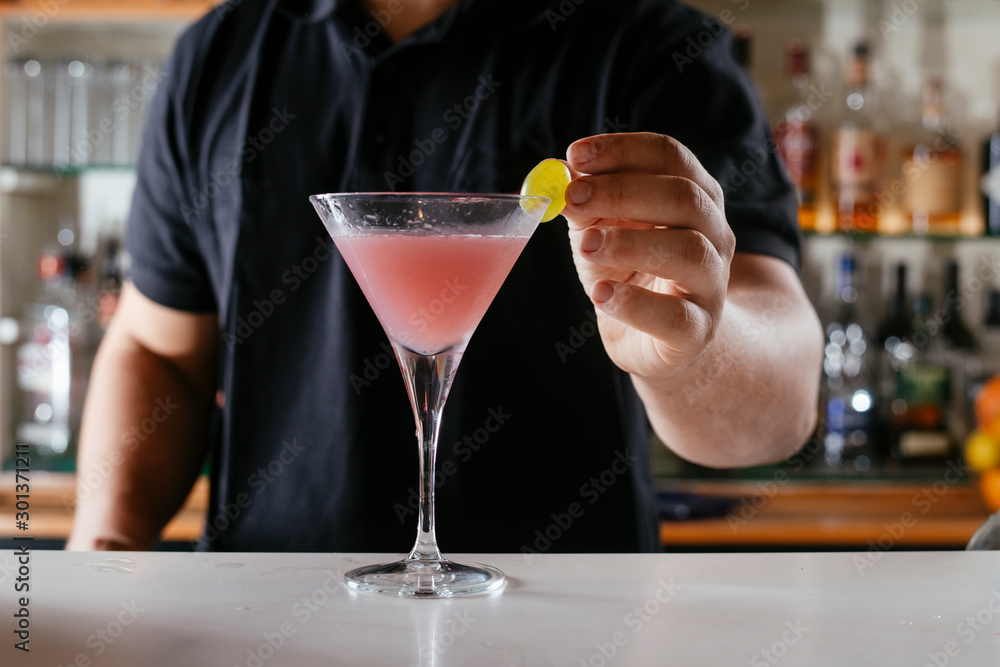 Professional barman making cosmopolitan cocktail. Professional barman making cosmopolitan cocktail.