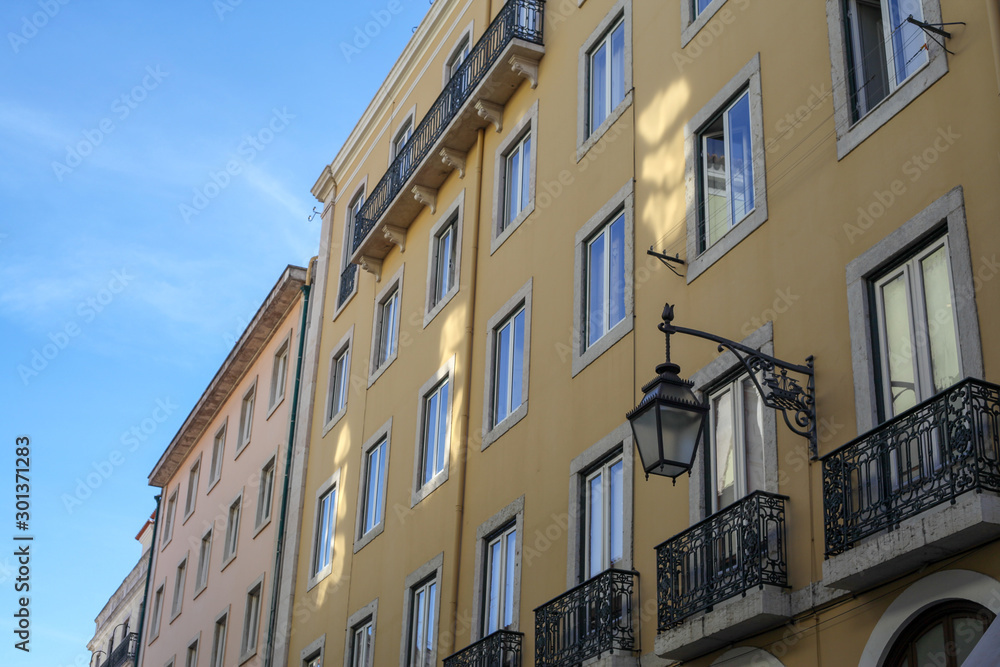 The traditional facade wall architectures of buildings with large glass doors and windows, balconies and iron lamps in the city of Rome in Italy