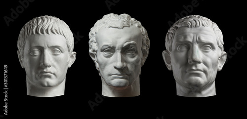 Three gypsum copy of ancient statue heads isolated on a black background. Plaster sculpture mans faces.