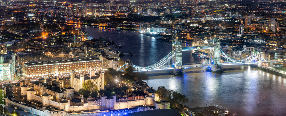 Luftaufnahme der berühmten Tower Brücke und des Towers von London am Abend mit urbanen Lichtern, Großbritannien