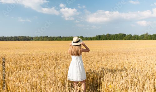 nature, harvest and people concept - portrait of smiling young girl in straw hat on cereal field in summer