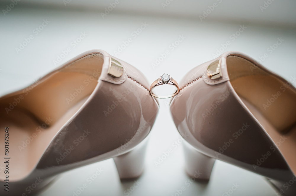 Pair of golden wedding rings between pair of a white shoes Pair of golden wedding rings between pair of a white shoes